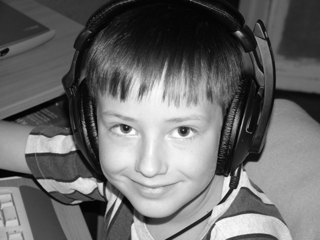 malý kluk poslouchající hudbu skrze velká sluchátka